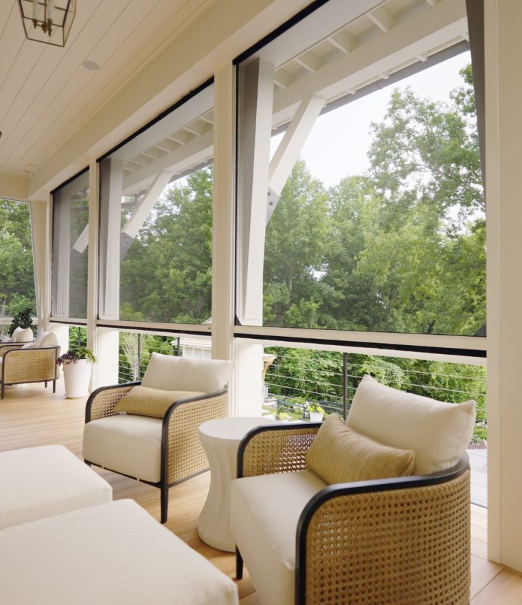 a large outdoor porch on a luxury home with cusioned outdoor chairs and retractible screens